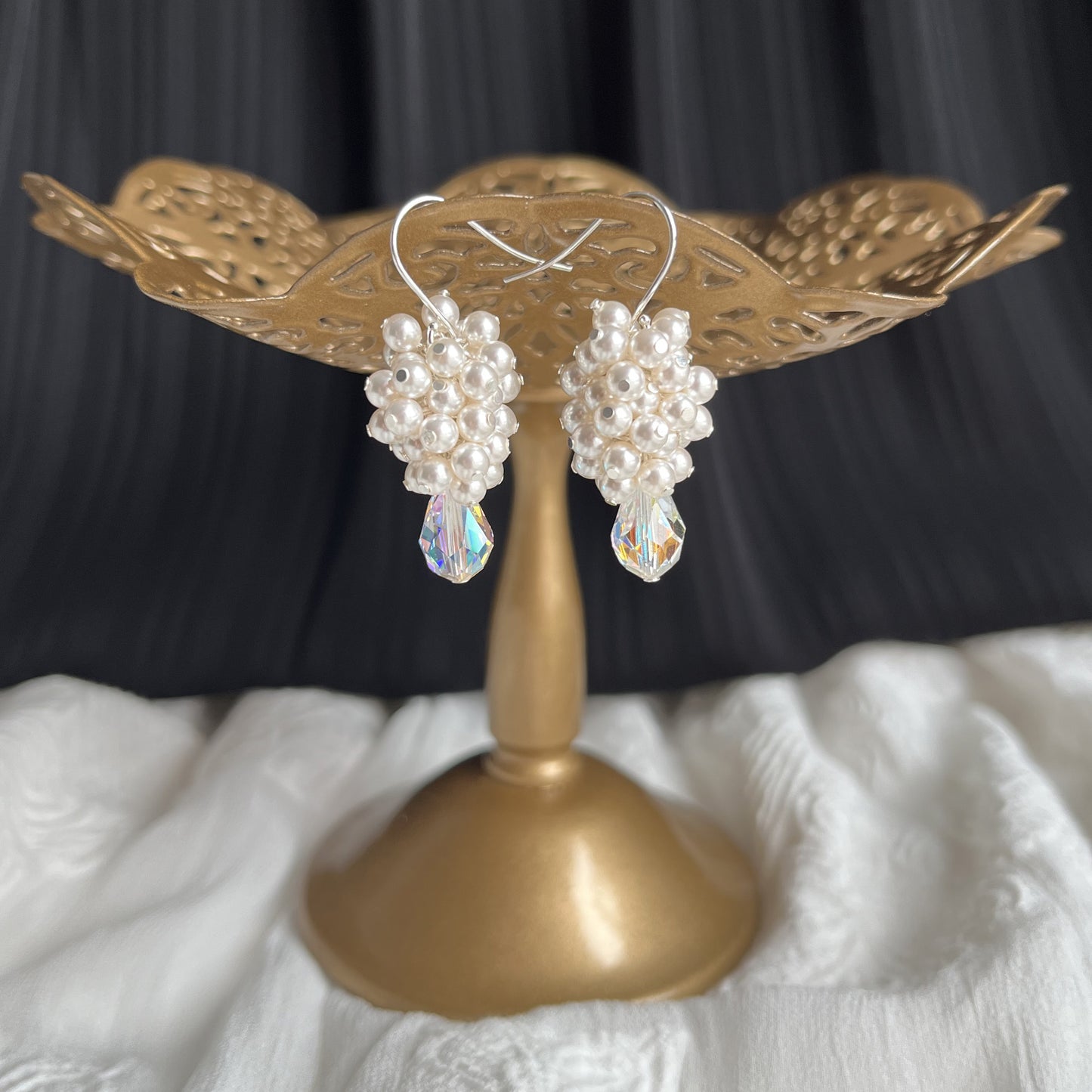 White pearl and crystal drop earrings on a brass stand, handcrafted for elegant bridal styling.