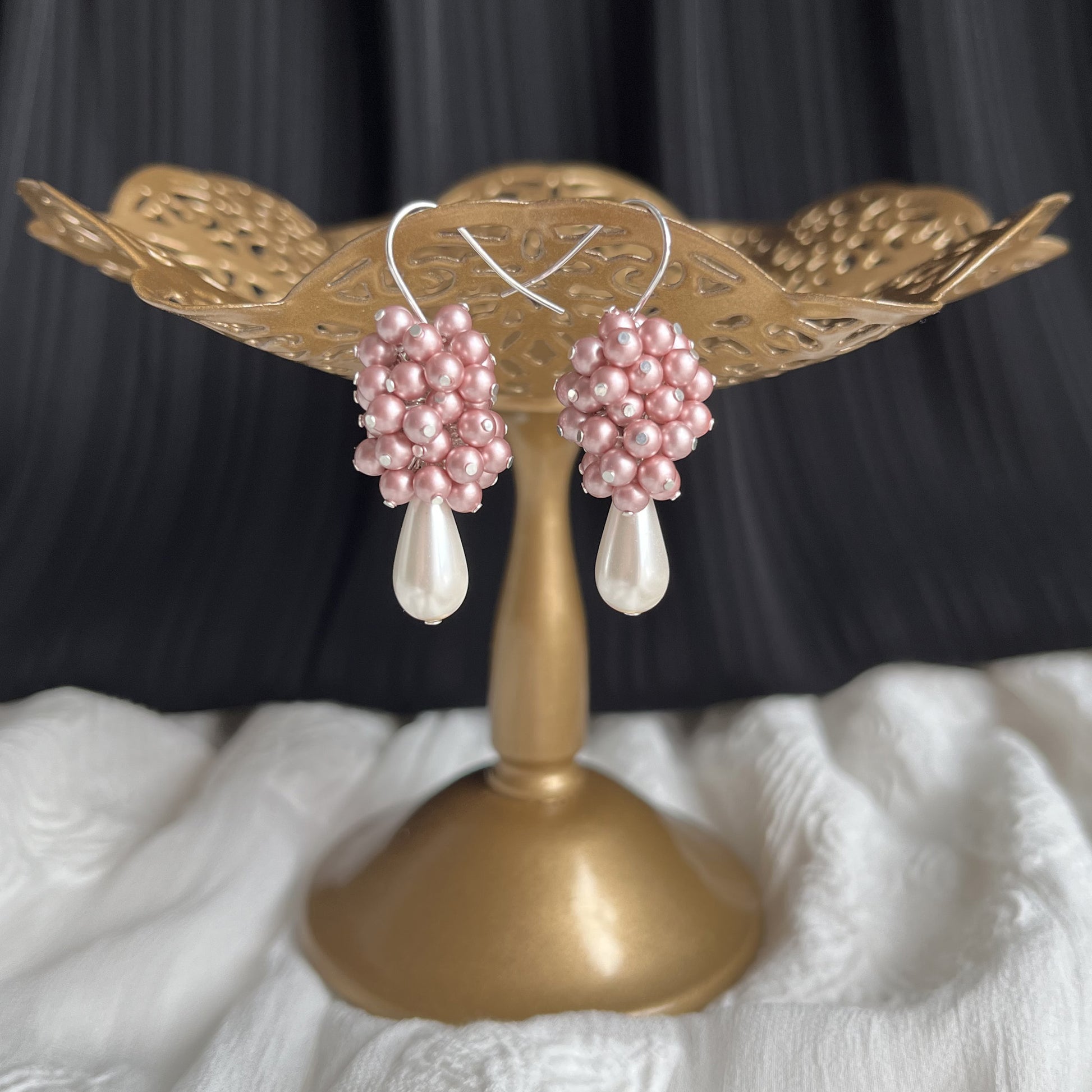 Pink pearl cluster drop earrings on a brass earring stand, delicate and softly feminine.