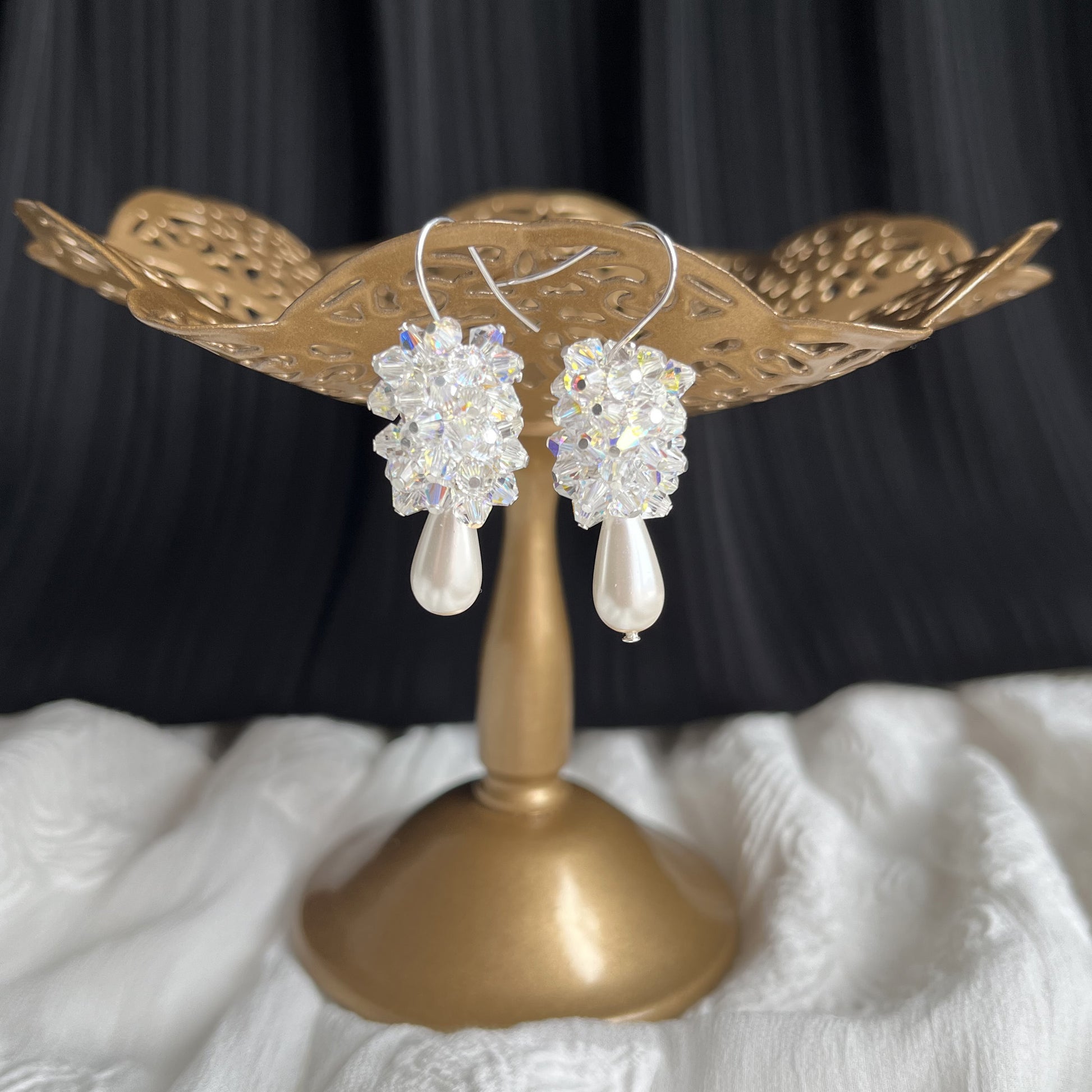 White pearl and crystal cluster drop earrings shown on a brass stand, elegant and handcrafted.