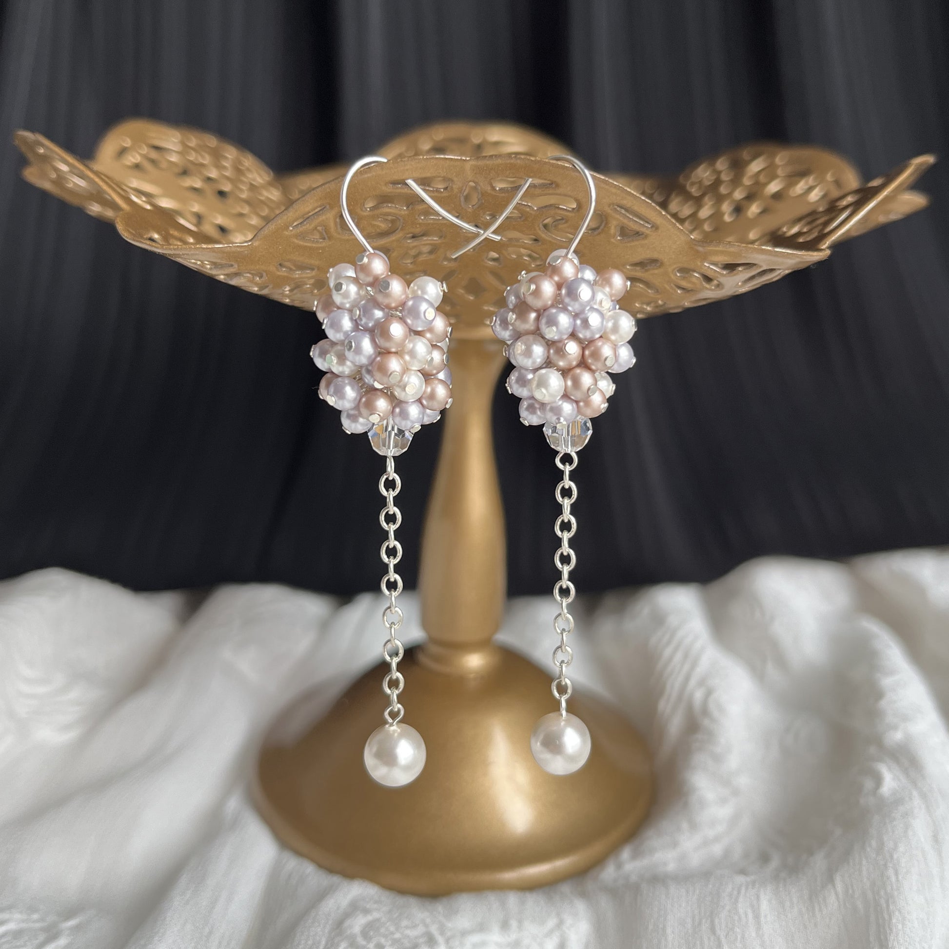 Lavender and almond pearl cluster earrings shown on a brass stand, romantic and naturally soft.