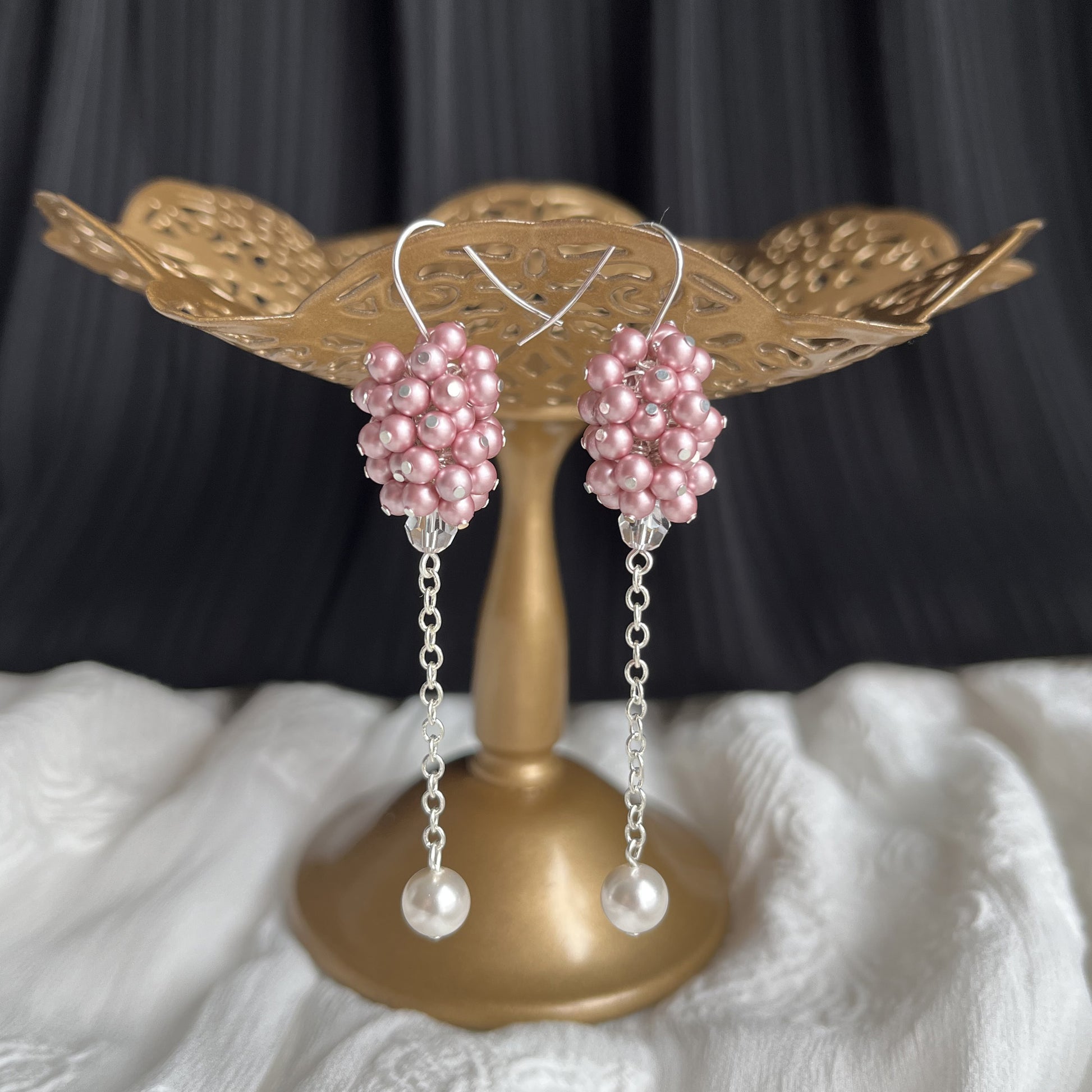 Pink pearl cluster earrings shown on a brass earring stand, romantic and softly luminous.