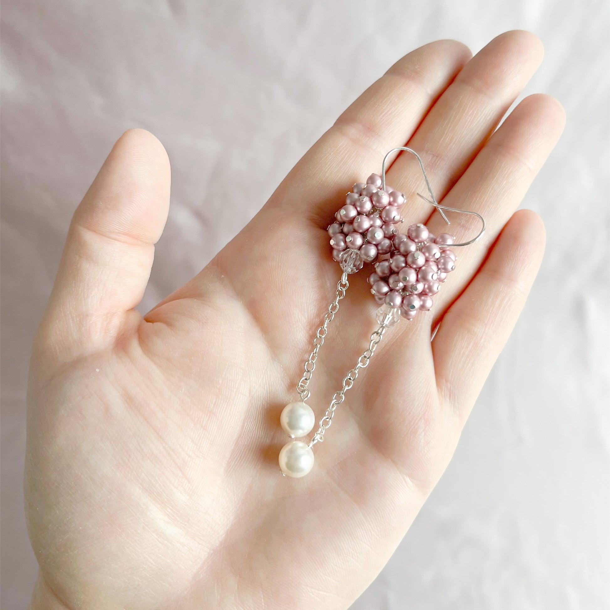 Pink pearl cluster earrings shown on an open hand to highlight size and soft handcrafted detail.