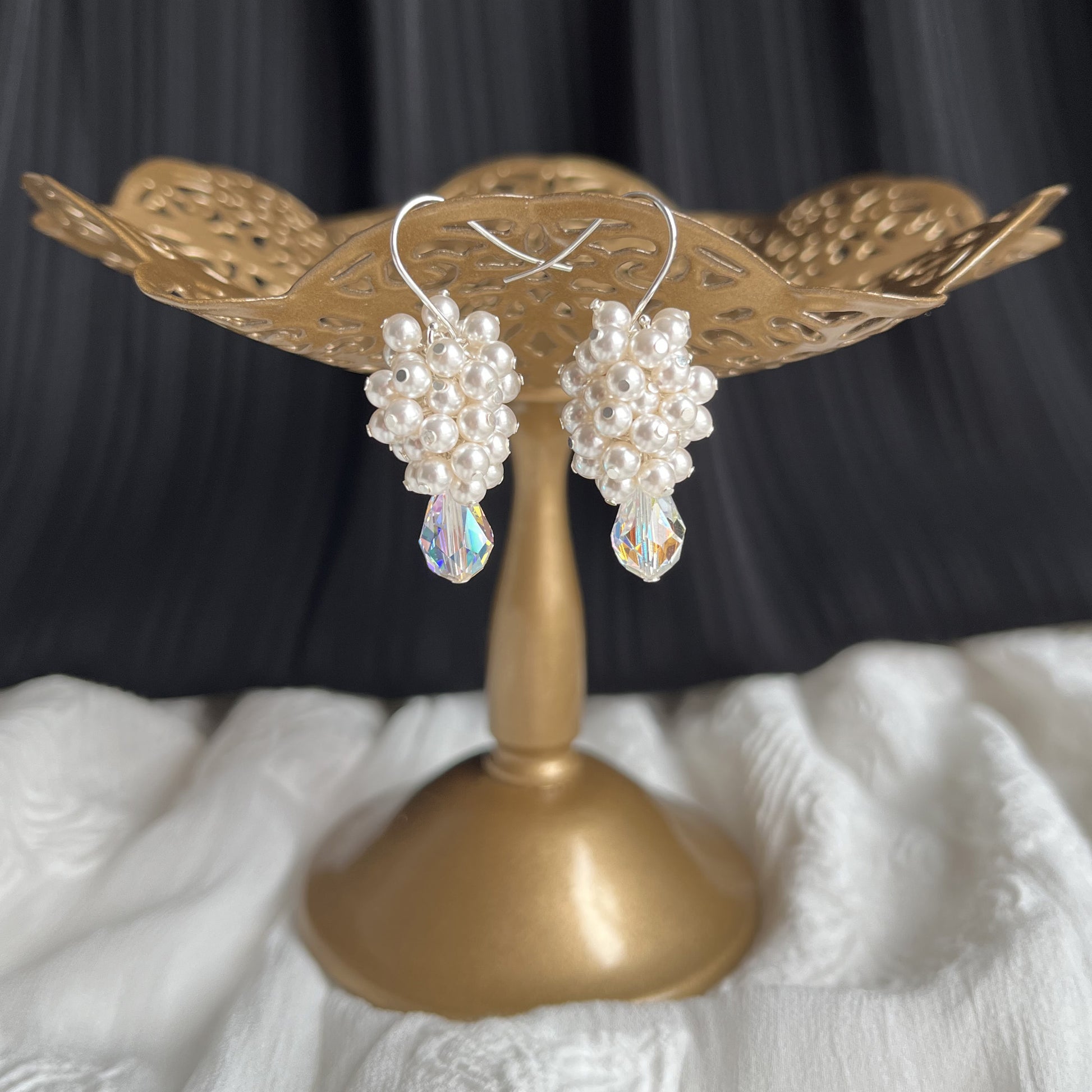 White pearl and crystal drop earrings on a brass stand, handcrafted for elegant bridal styling.