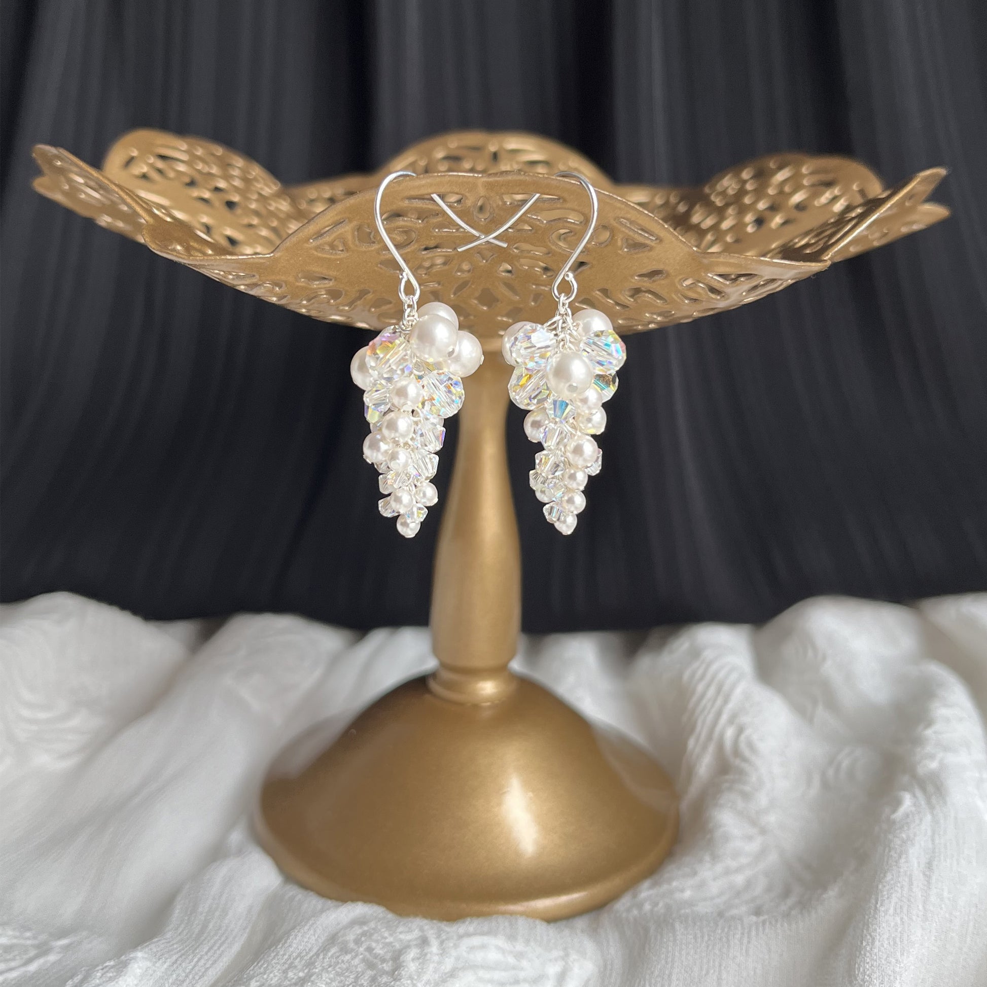 White pearl and crystal dangle earrings displayed on a brass earring stand, handcrafted and romantic.